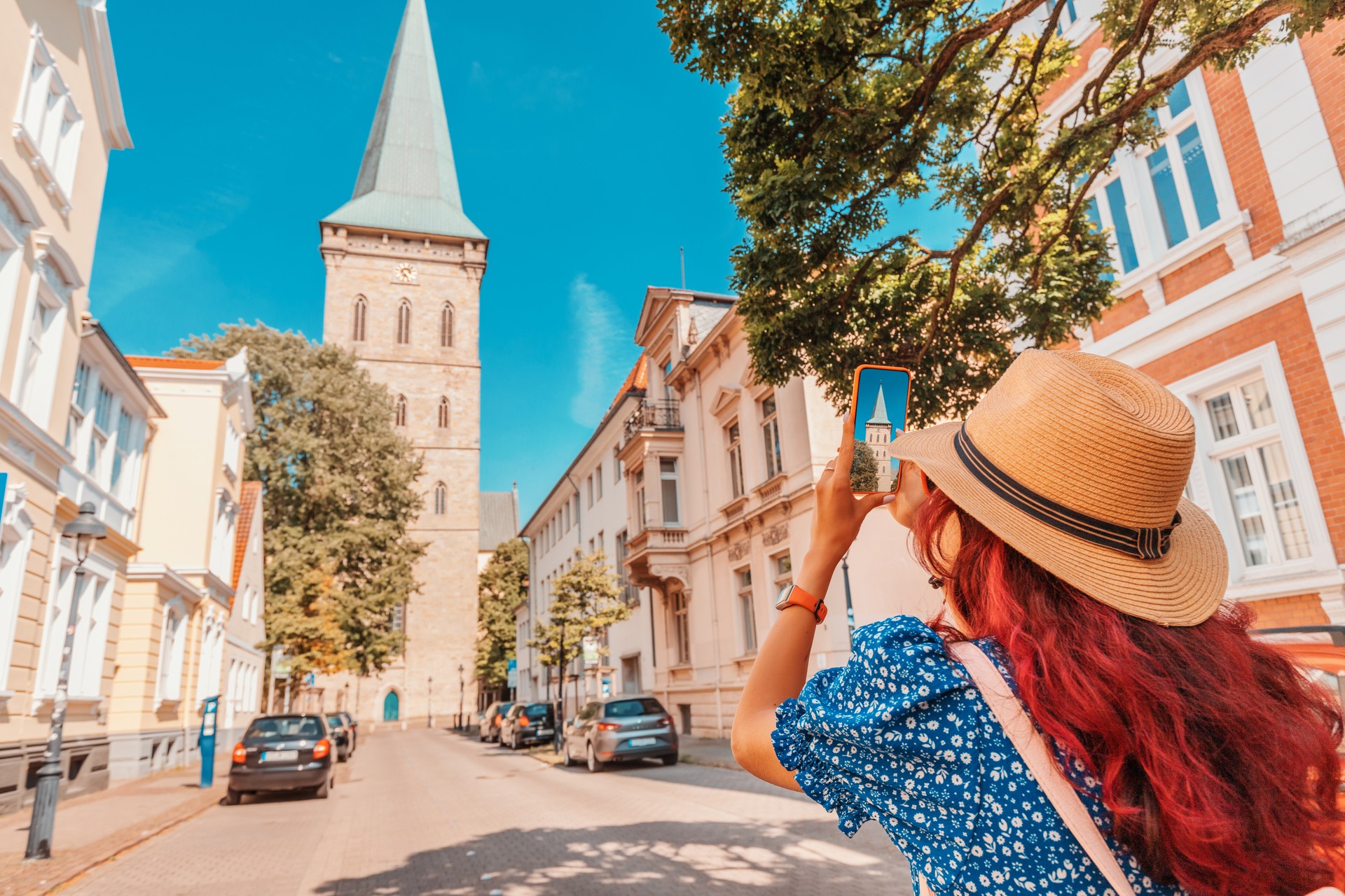 Travel blogger takes photos on the camera of smartphone of the Osnabruck Church building in old town, Germany